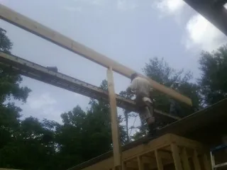 Carpenter setting a ridge beam over a new addition frame — Ice Dam Removal by Roofing Brothers in Rudd