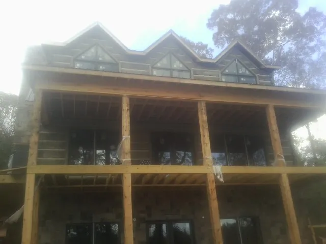 Dormers and porch framing on a large log home under construction — Roof Coating work by our crew in Rudd