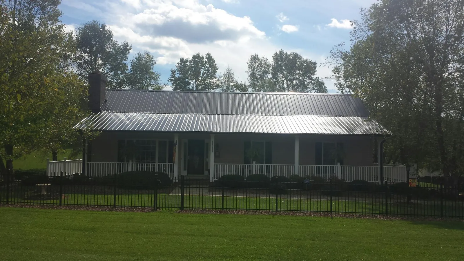 Gray metal roof on a brick ranch with a full width front porch — Gutter Guard Installation work by our crew in Rudd