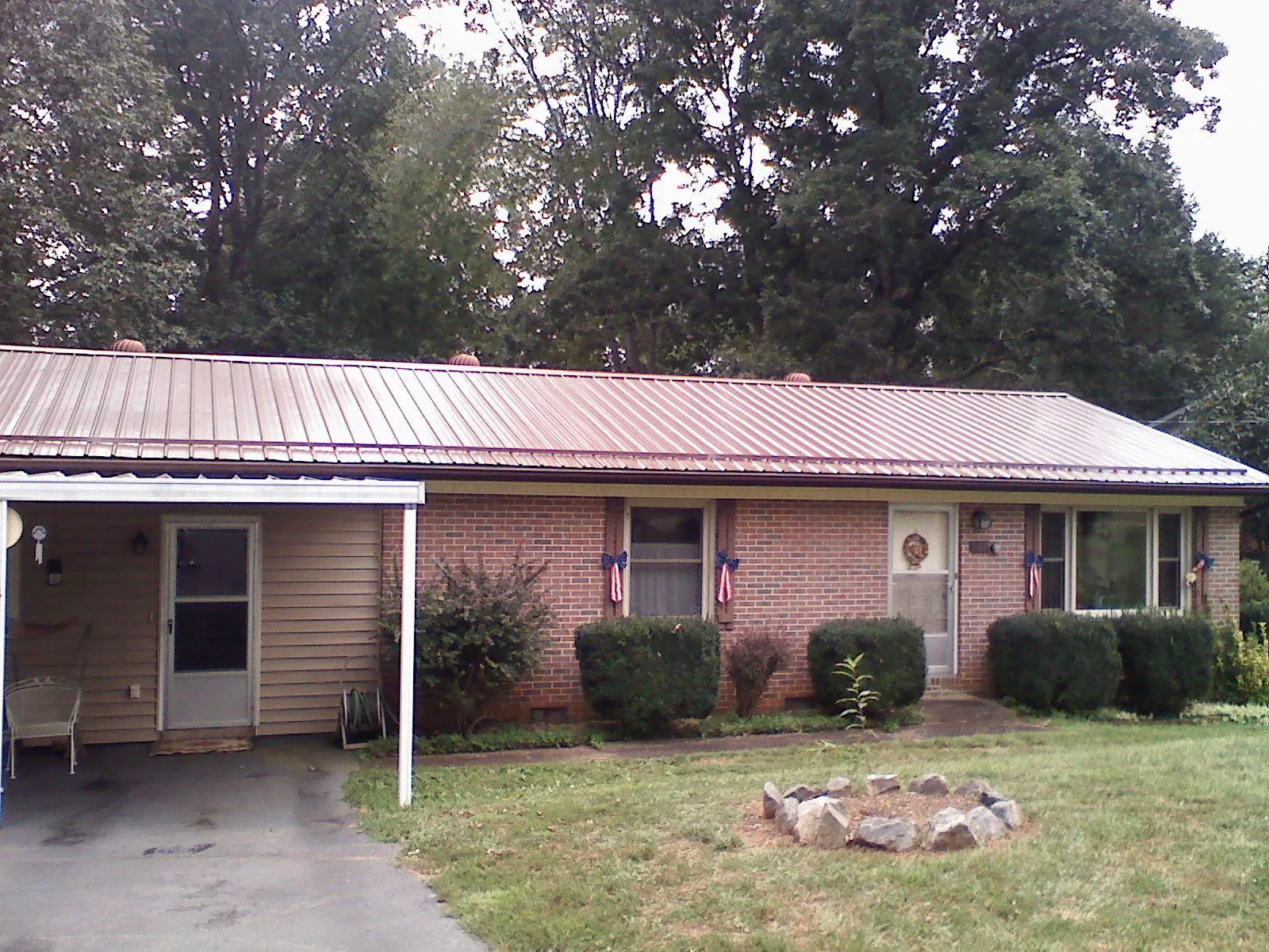 Bronze metal roof and carport on a brick ranch home — Roof Repair work by our crew in Rudd