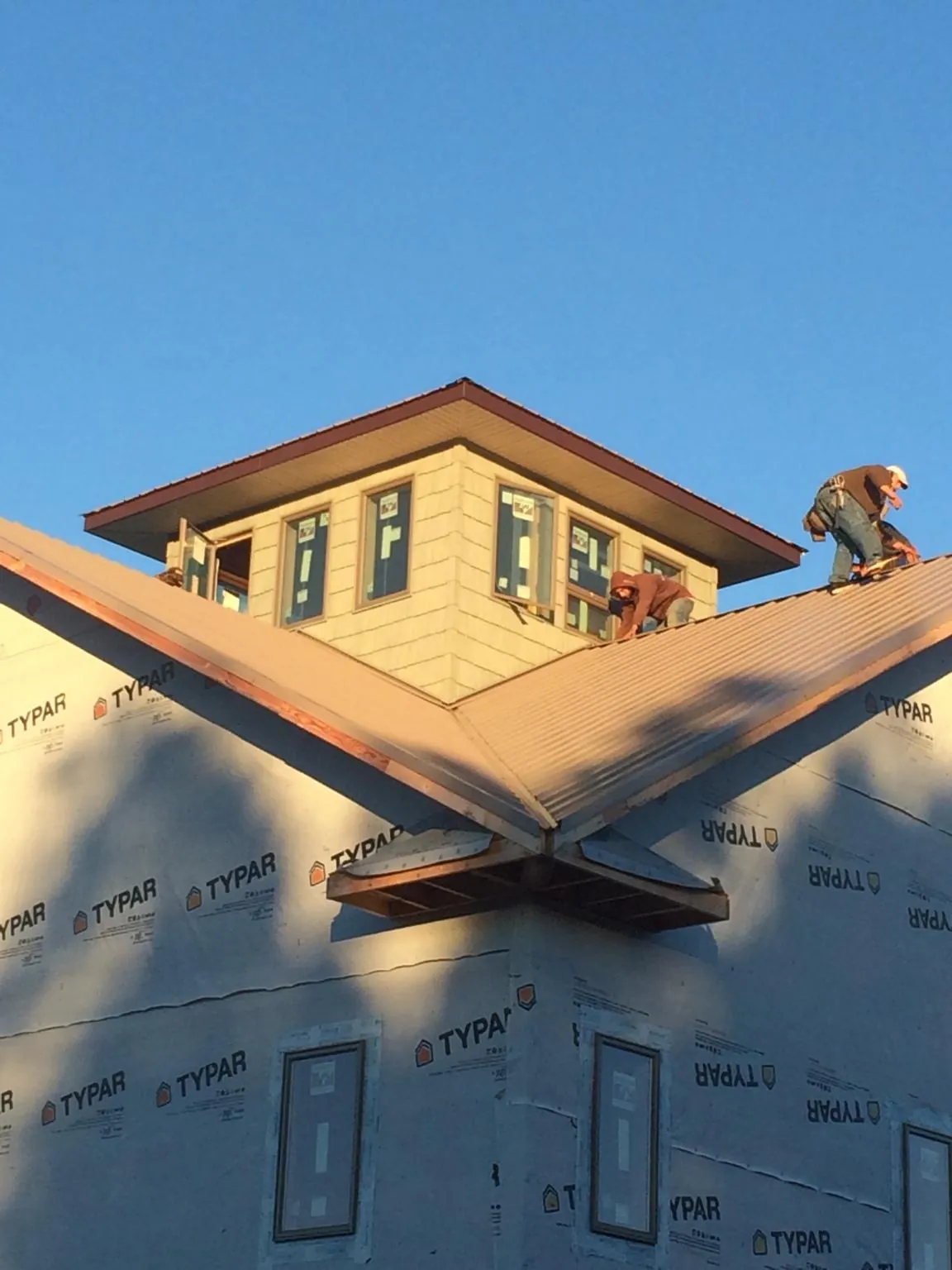 Roofers working around a rooftop cupola on a new metal roof at sunset — Roof Waterproofing in Rudd by Roofing Brothers